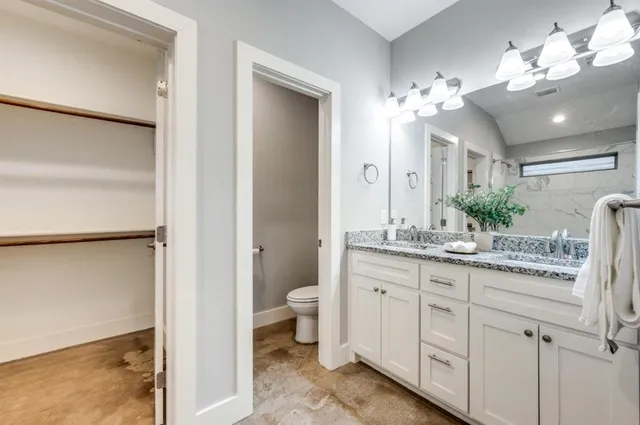 a bathroom with a granite countertop sink a toilet and a mirror