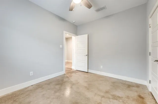 an empty room with a ceiling fan and carpet