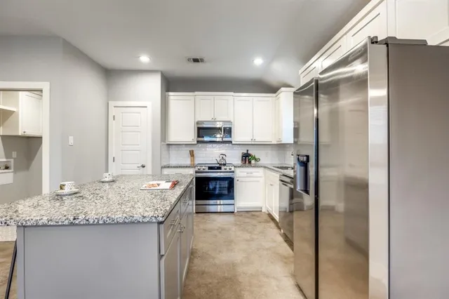 a kitchen with stainless steel appliances granite countertop a refrigerator sink stove and oven