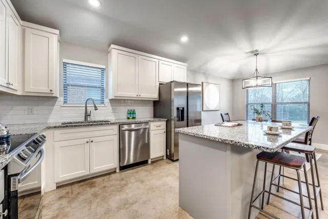 a kitchen with granite countertop white cabinets and stainless steel appliances