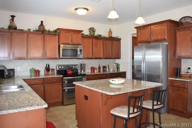 8067 Bryson Road Indian Land, SC 29707 - Photo 8 of 22 a kitchen with granite countertop a table chairs stove and refrigerator