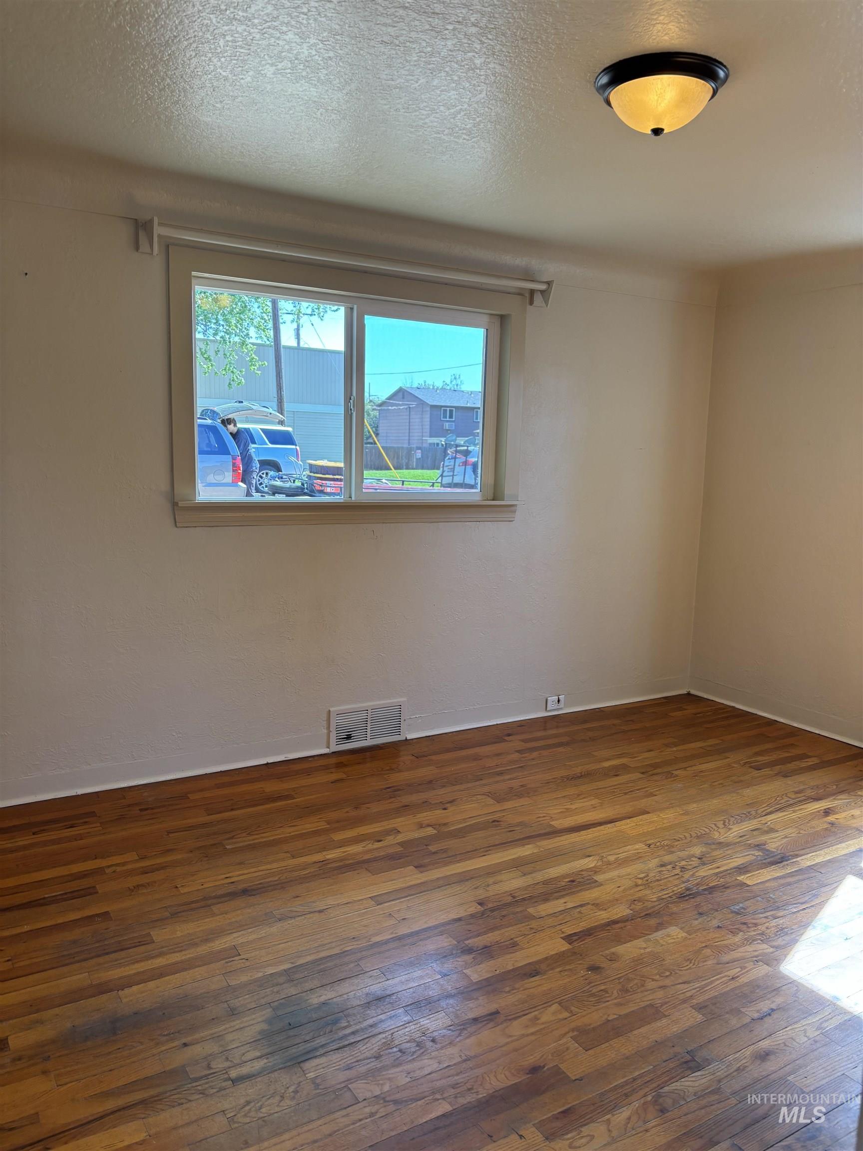 5116 West Morris Hill Road Boise, ID 83706 - Photo 13 of 19 Wood-finish flooring with baseboard trim, neutral wall tones, and an overhead flush-mount light fixture