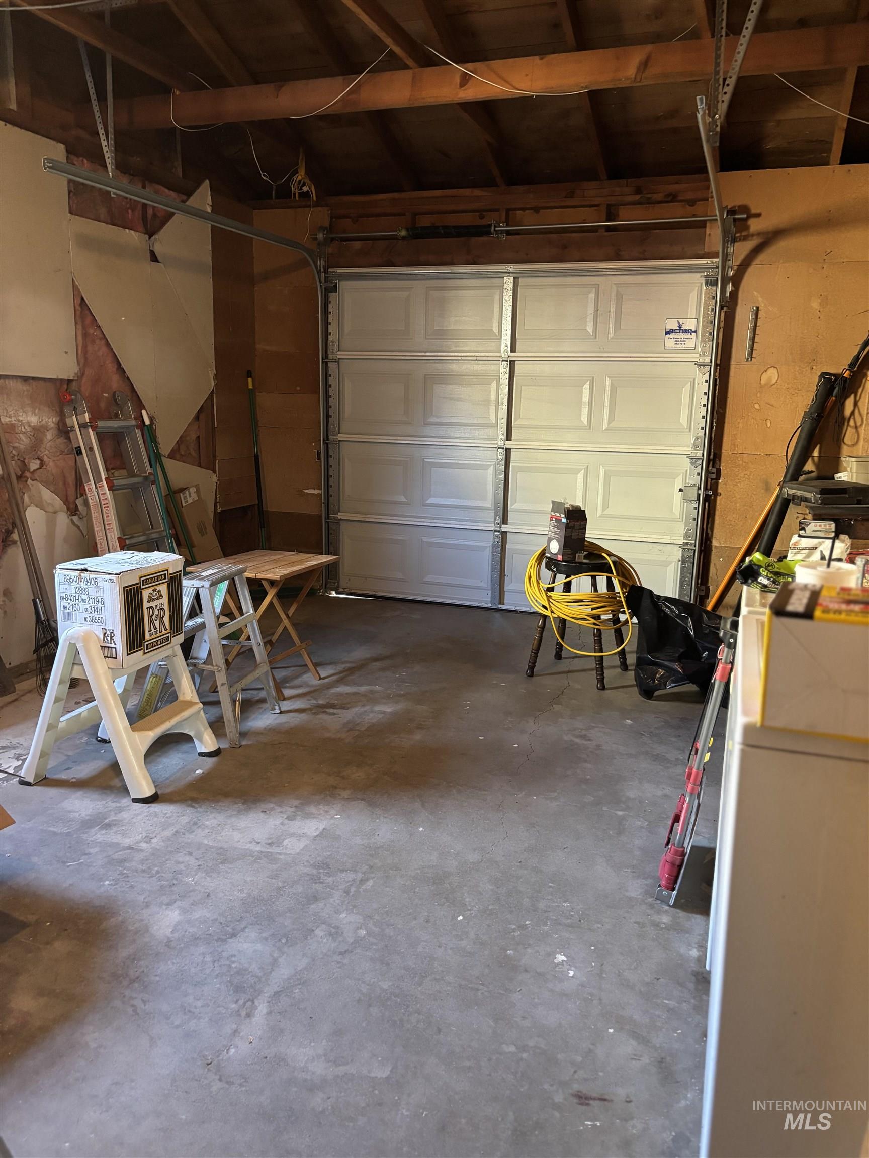 5116 West Morris Hill Road Boise, ID 83706 - Photo 19 of 19 Single-car garage featuring a white paneled garage door and exposed wood beam ceiling