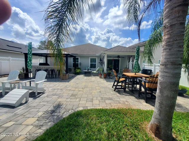 a view of a patio with table and chairs under an umbrella with large trees
