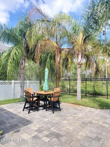 a view of a patio with table and chairs potted plants and palm trees