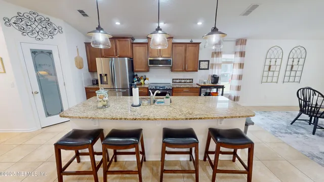 a kitchen with granite countertop kitchen island stainless steel appliances a dining table and chairs