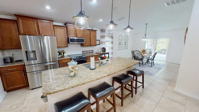 a kitchen with granite countertop a table chairs microwave and refrigerator