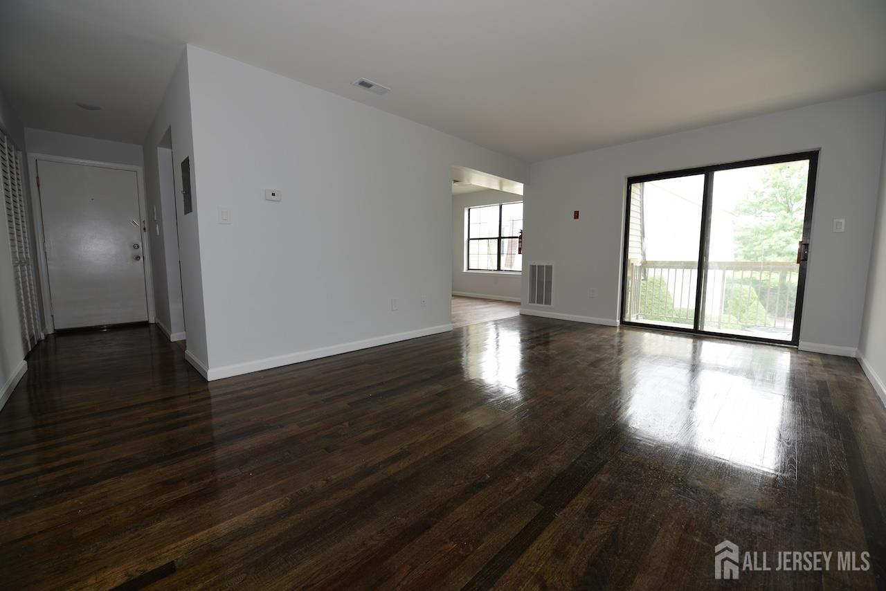 307 Hidden Village Drive Perth Amboy, NJ 08861 - Photo 1 of 18 a view of an empty room with wooden floor and a window