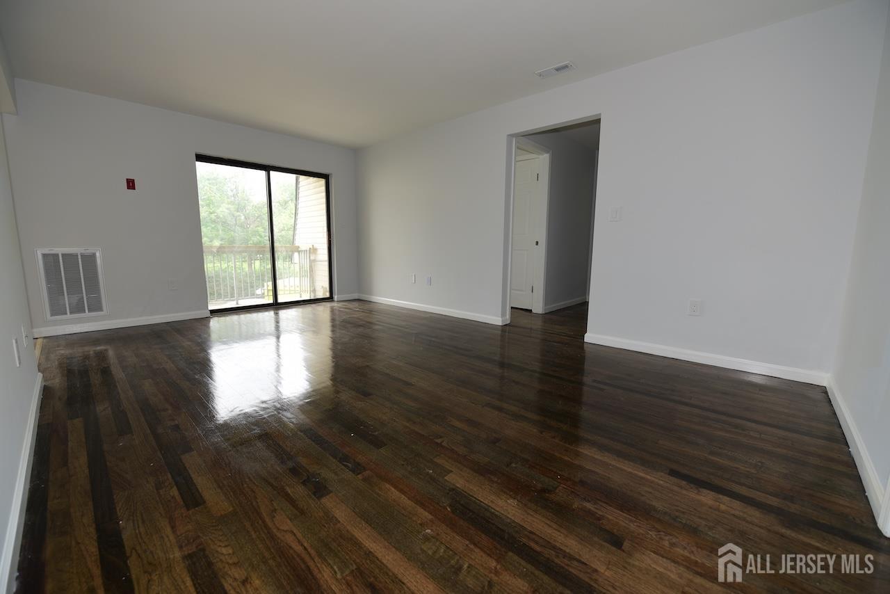 307 Hidden Village Drive Perth Amboy, NJ 08861 - Photo 2 of 18 a view of an empty room with wooden floor and a window