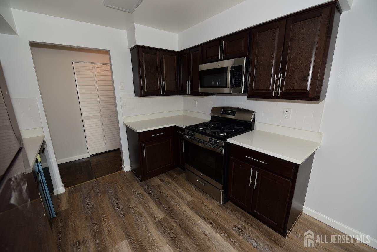 307 Hidden Village Drive Perth Amboy, NJ 08861 - Photo 3 of 18 a kitchen with wooden cabinets and black appliances