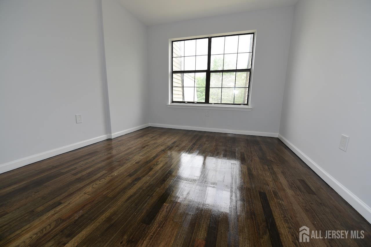 307 Hidden Village Drive Perth Amboy, NJ 08861 - Photo 7 of 18 an empty room with wooden floor and windows