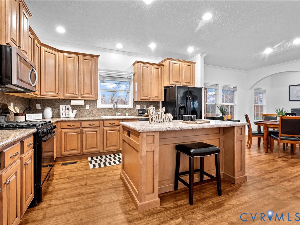 10885 Zilles Road Wilsons, VA 23894 - Photo 15 of 44 a kitchen with stainless steel appliances granite countertop a stove top oven a sink dishwasher and a refrigerator with wooden floor