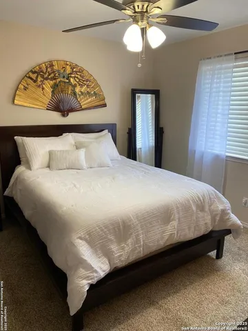 a large bed sitting in a bedroom next to a window and a chandelier