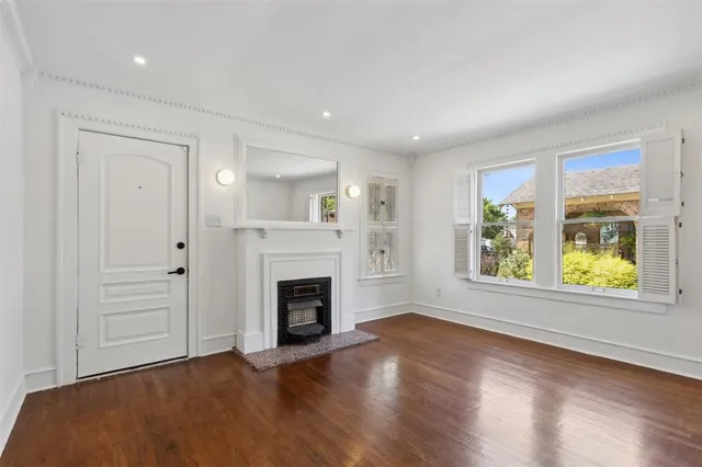 an empty room with windows a fireplace and wooden floor