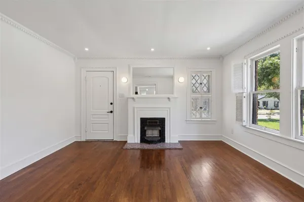 a view of an empty room with wooden floor fireplace and a window