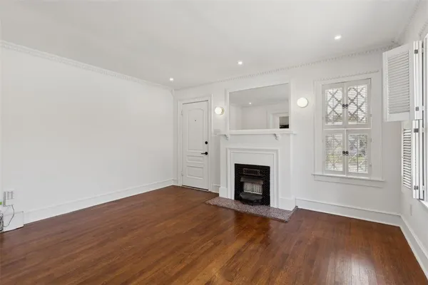 an empty room with windows a fireplace and wooden floor