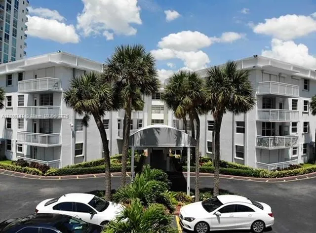 a front view of a building with parking space and car parked