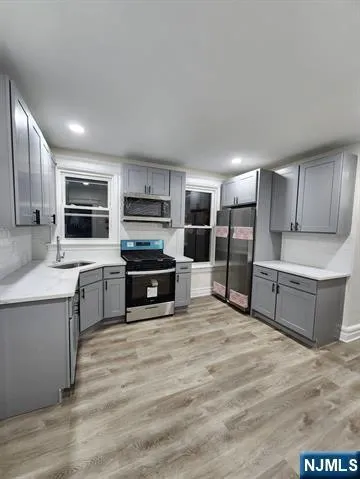 a large kitchen with cabinets wooden floor and stainless steel appliances