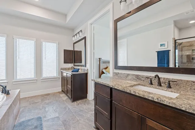 a bathroom with a granite countertop sink mirror and a bathtub