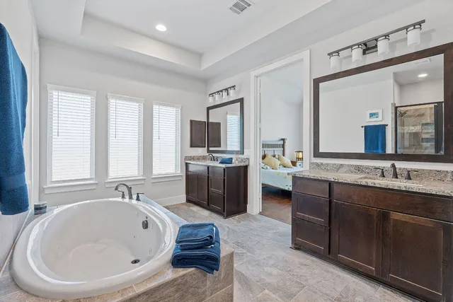 a large bathroom with a double vanity sink a mirror a bathtub and window