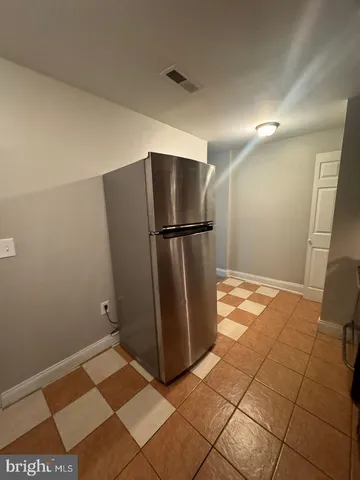 a view of a refrigerator in kitchen and an empty room