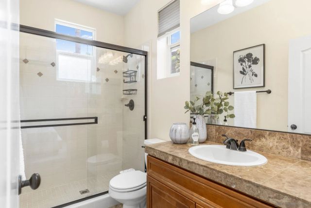 a bathroom with a granite countertop sink a toilet and shower