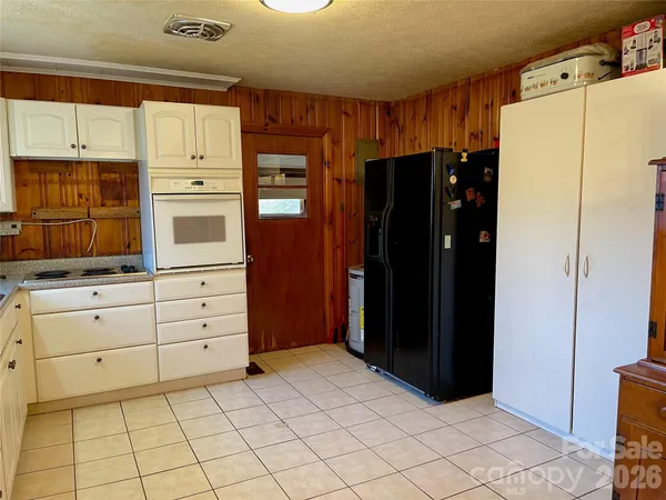 a kitchen with white cabinets and refrigerator