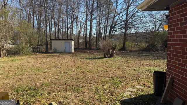 a view of a backyard with large trees and wooden fence