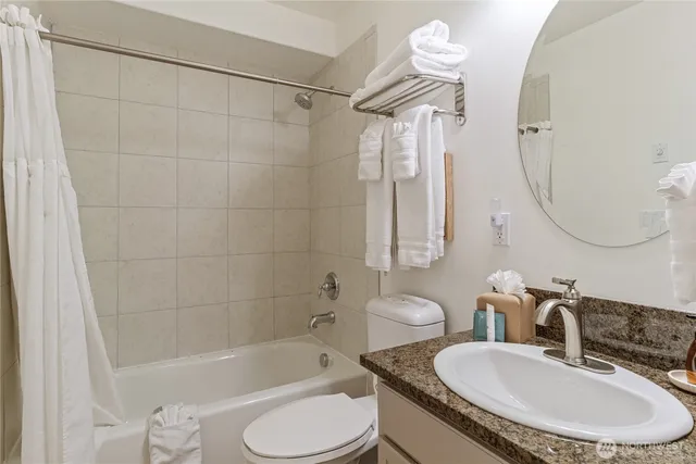 a bathroom with a granite countertop sink mirror toilet and bathtub