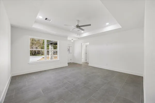 an empty room with a ceiling fan and windows