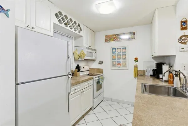 a kitchen with granite countertop a refrigerator a stove a sink a counter top space and cabinets