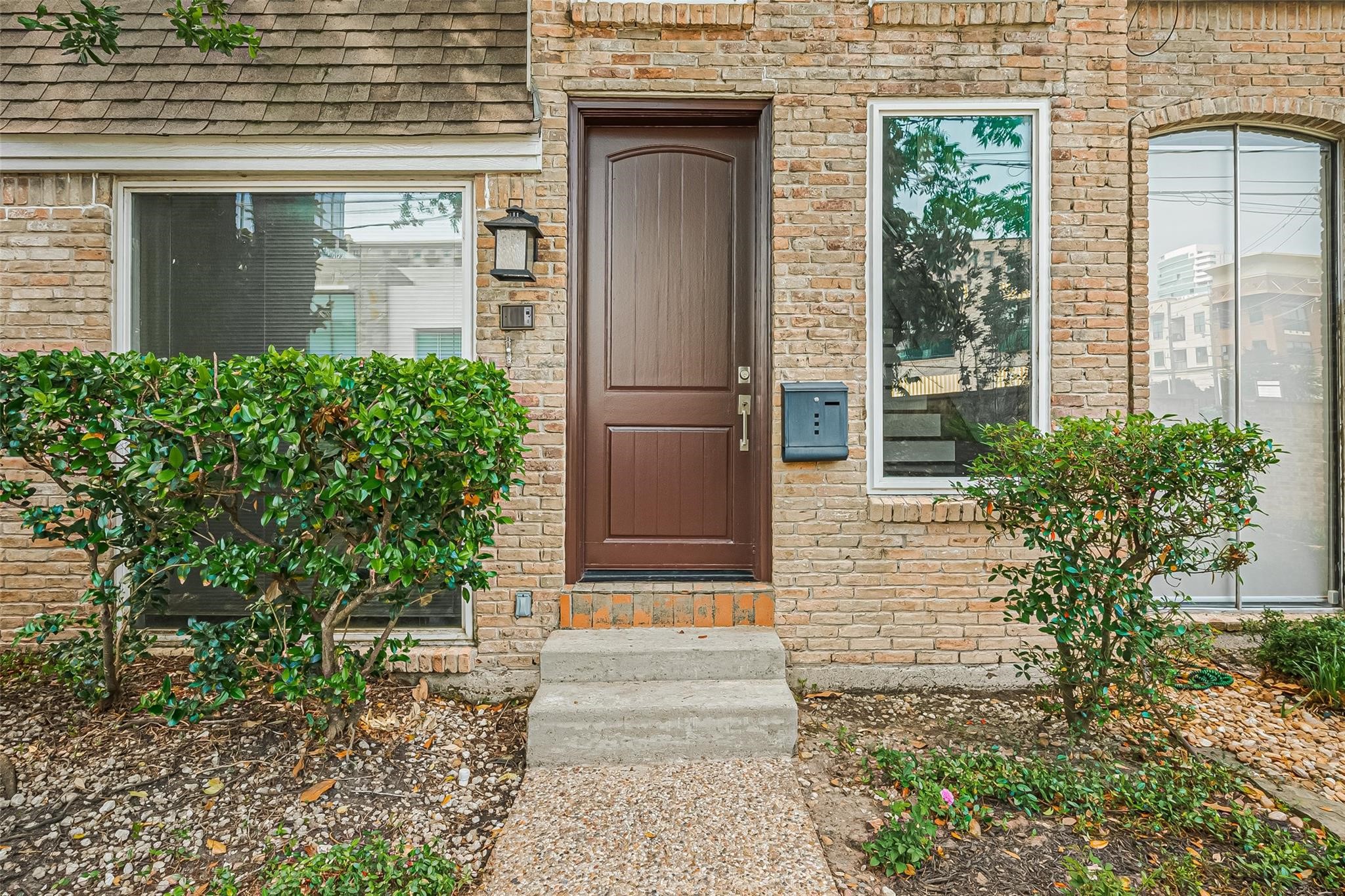 4305 Westheimer Road Houston, TX 77027 - Photo 2 of 25 Charming brick townhouse exterior with a welcoming front door, framed by lush greenery and contemporary windows.