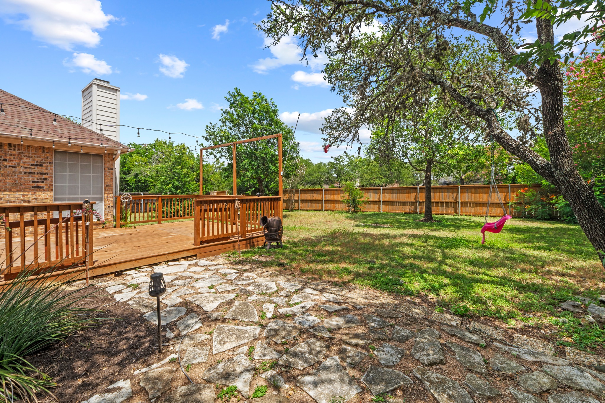 8605 Axis Drive Austin, TX 78749 - Photo 33 of 38 A spacious backyard retreat features a newly constructed wooden deck and a flagstone patio, perfect for outdoor enjoyment.