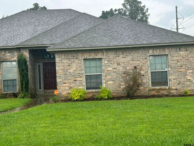 a view of a house with brick walls and a yard with plants