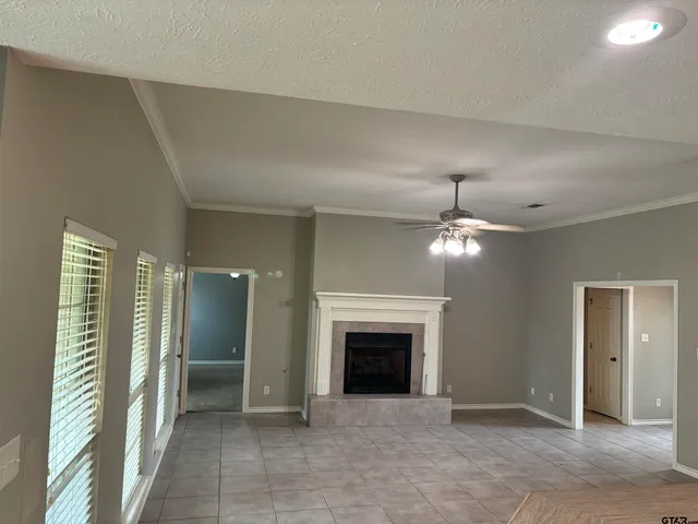 an empty room with fireplace and a chandelier fan