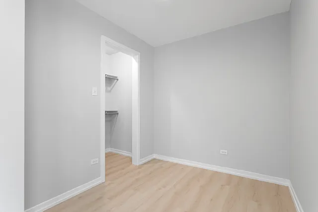 a view of an empty room with wooden floor and closet