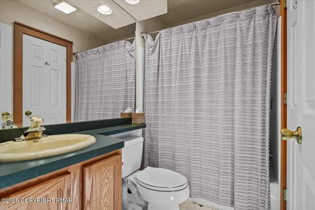 a bathroom with a granite countertop toilet a sink and mirror