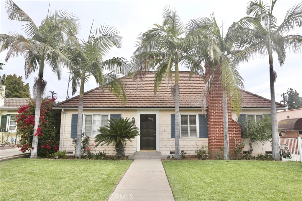 front view of a house with a yard and palm trees