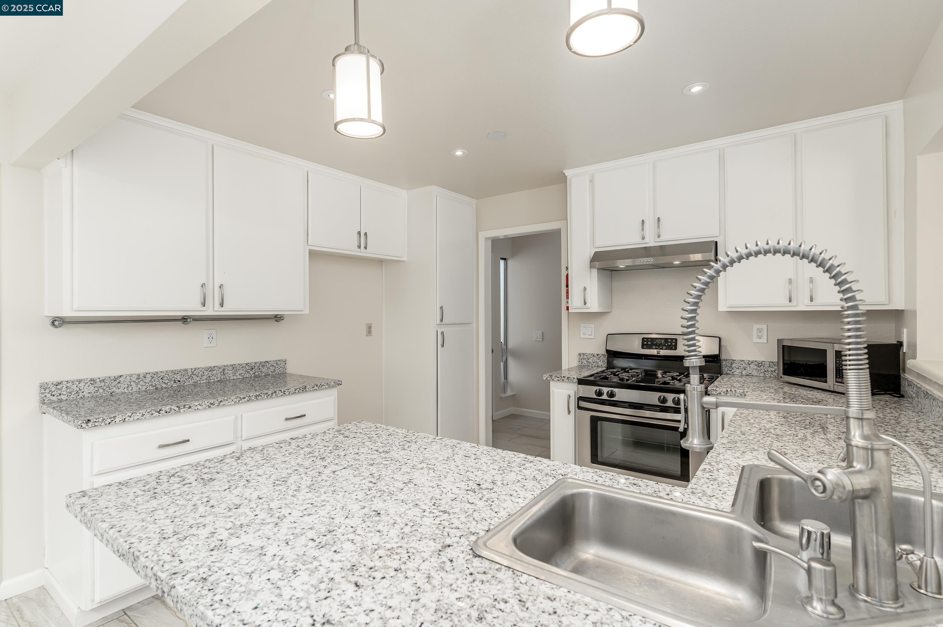 121 Brighton Street Hercules, CA 94547 - Photo 15 of 55 a kitchen with granite countertop a sink stainless steel appliances and white cabinets