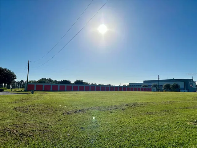 a view of a road with a big yard and palm trees