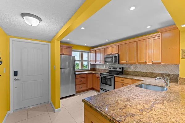 a kitchen with granite countertop stainless steel appliances a refrigerator cabinets and microwave