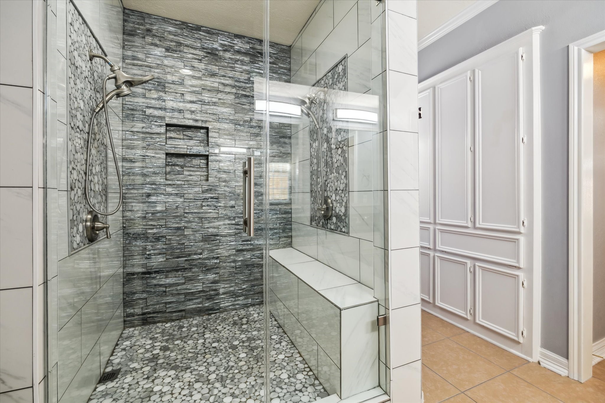 7671 Ameswood Road Houston, TX 77095 - Photo 12 of 23 New primary shower in 2022. Double shower faucets with hand wands, impressive glass tiles and a toiletry niche. Sublime marble tile accents in the floor and walls. A bench seat and glass door complete this attractive shower.