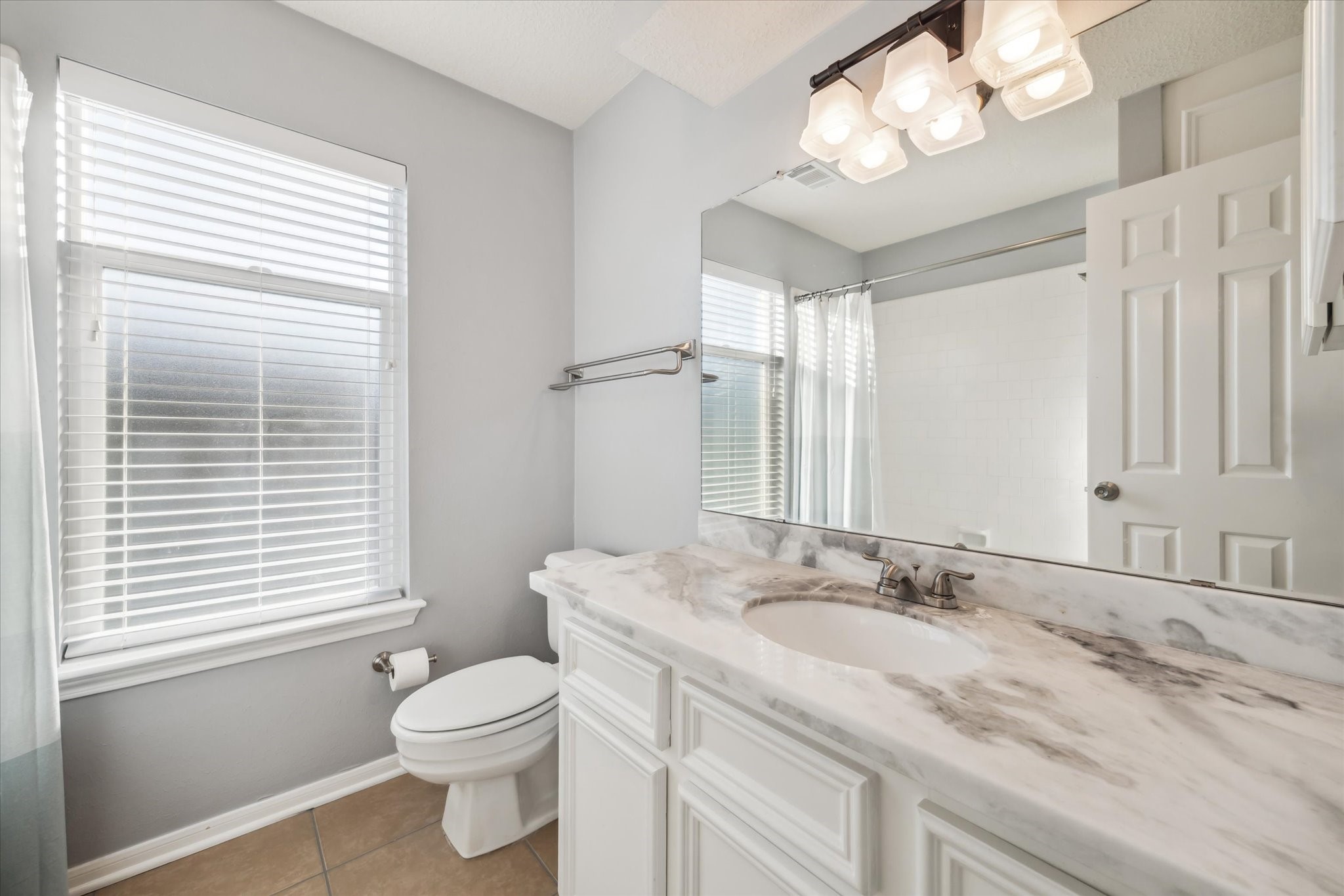 7671 Ameswood Road Houston, TX 77095 - Photo 17 of 23 This upstairs full bathroom was renovated in 2022. It is light and bright with a white tub/shower, vanity with beautiful marble countertop, white and gray paint and brushed nickel fixtures.