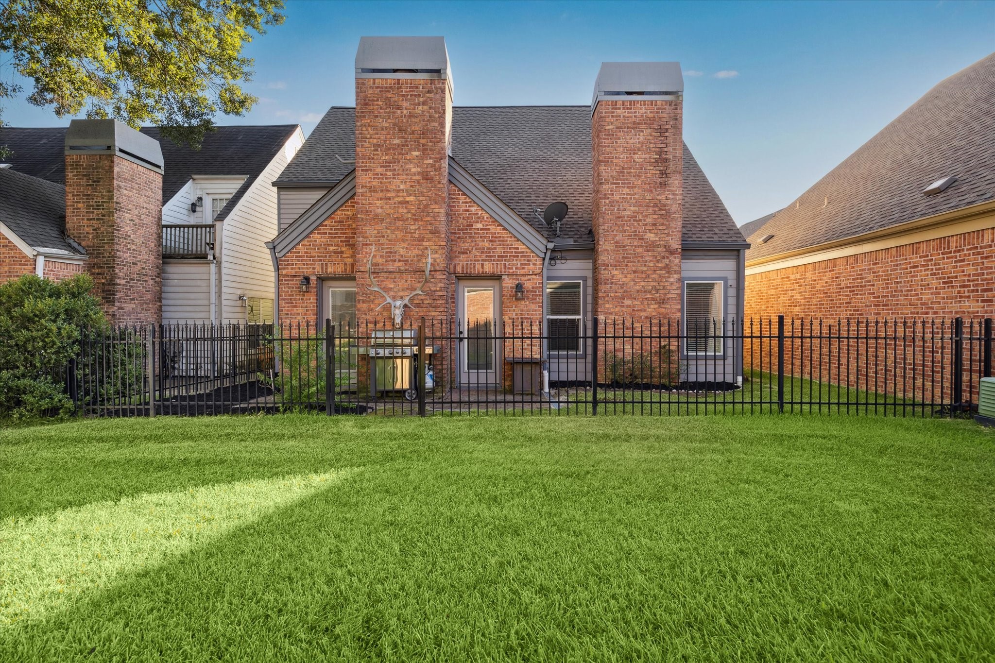 7671 Ameswood Road Houston, TX 77095 - Photo 2 of 23 7671 Ameswood is fuly fenced including the iron fence that allows breezes to billow through this enclosed patio area. Greenspaces within this community are maintained by the HOA.