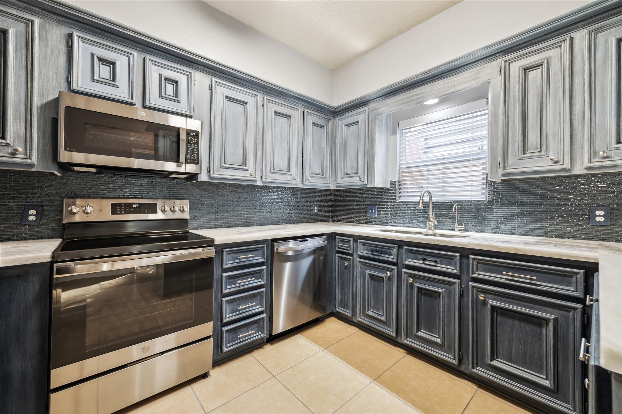 7671 Ameswood Road Houston, TX 77095 - Photo 8 of 23 New stainless steel convection range with glass stove/ convection/microwave oven, stainless steel sink, faucet, disposal, marble countertops, glass tile backsplash, and reverse osmosis water dispenser, all new in 2022.