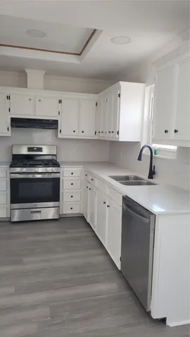 a kitchen with stainless steel appliances a stove a sink and white cabinets
