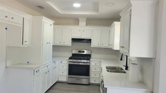 a kitchen with white cabinets and stainless steel appliances