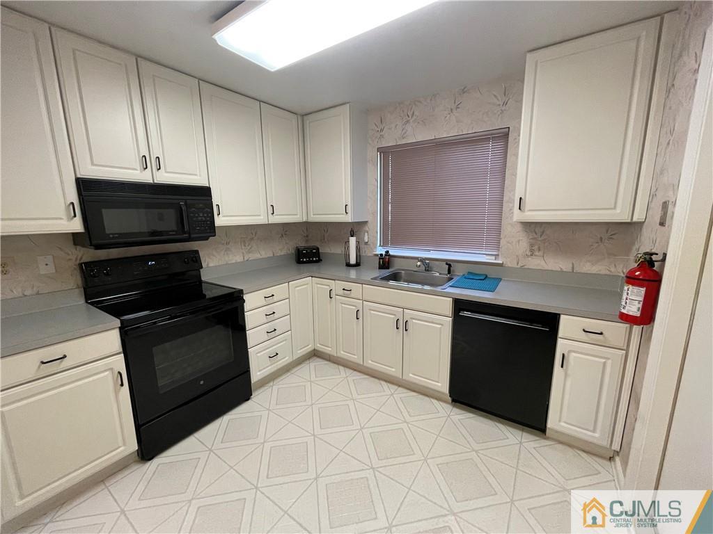 656 Nutley Drive, Unit A Monroe Township, NJ 08831 - Photo 8 of 25 a kitchen with granite countertop white cabinets sink and stainless steel appliances
