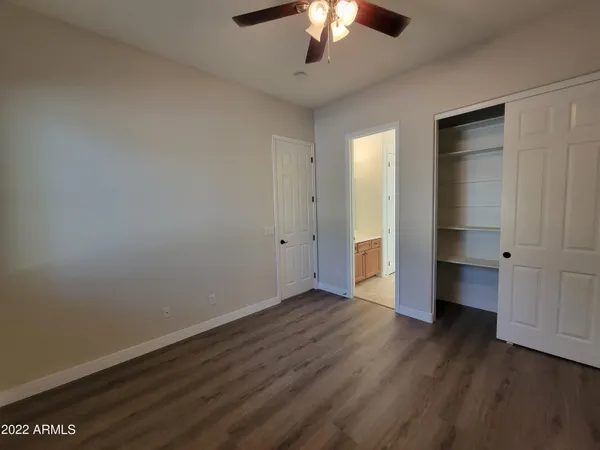 an empty room with wooden floor chandelier and windows