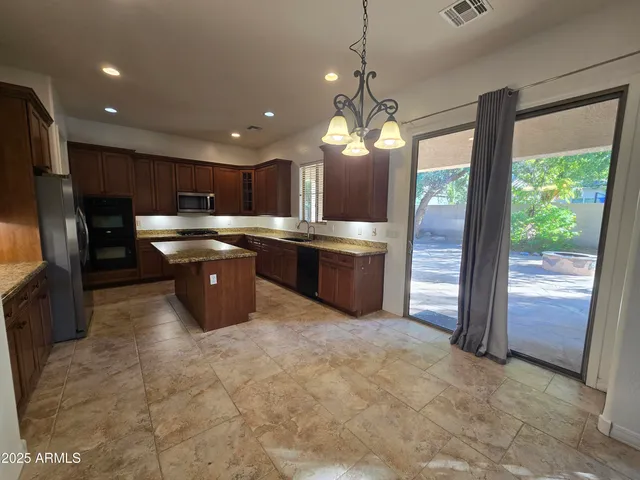 a open kitchen with kitchen island granite countertop a refrigerator a stove top oven a sink and dishwasher